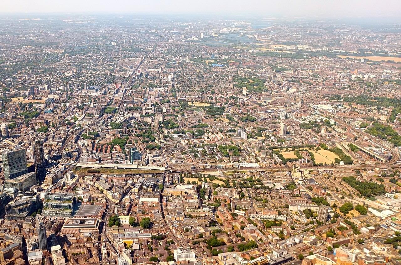 Aerial view of a dense city with roads, buildings, and green spaces extending to the horizon.